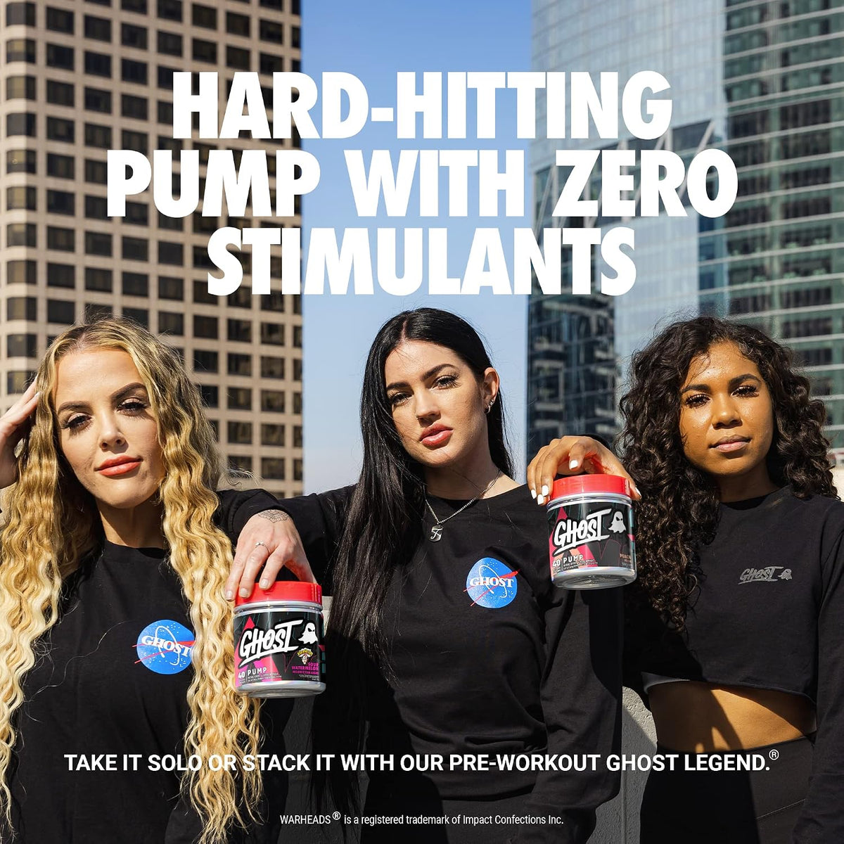 Three women standing outdoors in front of tall city buildings, each wearing a black shirt and holding a tub of Ghost pre-workout. Large white text at the top reads 'HARD-HITTING PUMP WITH ZERO STIMULANTS,' and additional text at the bottom references Ghost Legend and Mash+Eats.